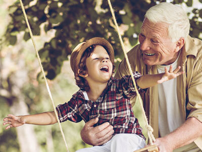 Grandpa playing with grandson on a swingset.