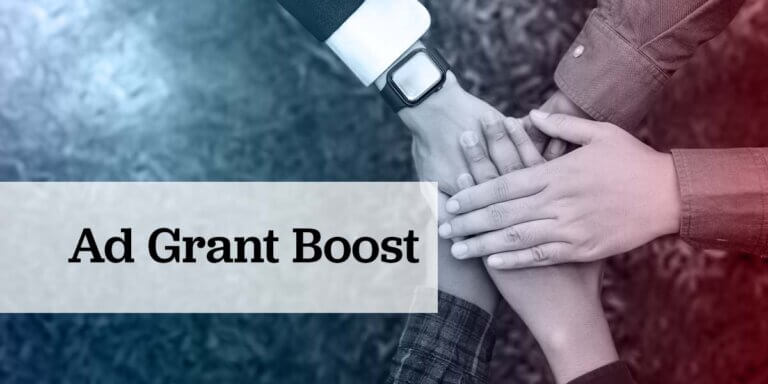 Hands from a diverse group of people stacked together in unity, overlaid with a cool blue to red gradient and the text “Ad Grant Boost” displayed on a translucent banner, symbolizing teamwork and the empowering impact of Google Ad Grants for nonprofits.