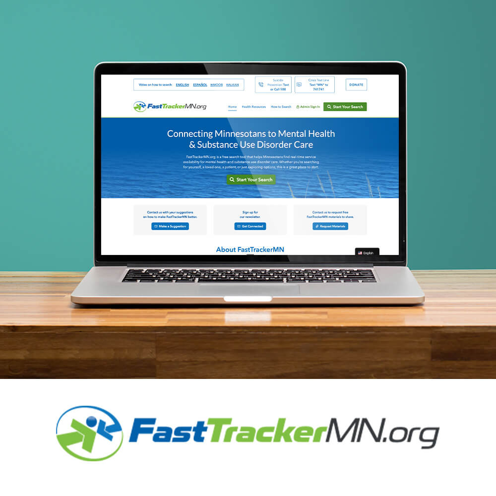 Laptop displaying the redesigned FastTrackerMN website on a wooden desk, with the FastTrackerMN.org logo shown below.